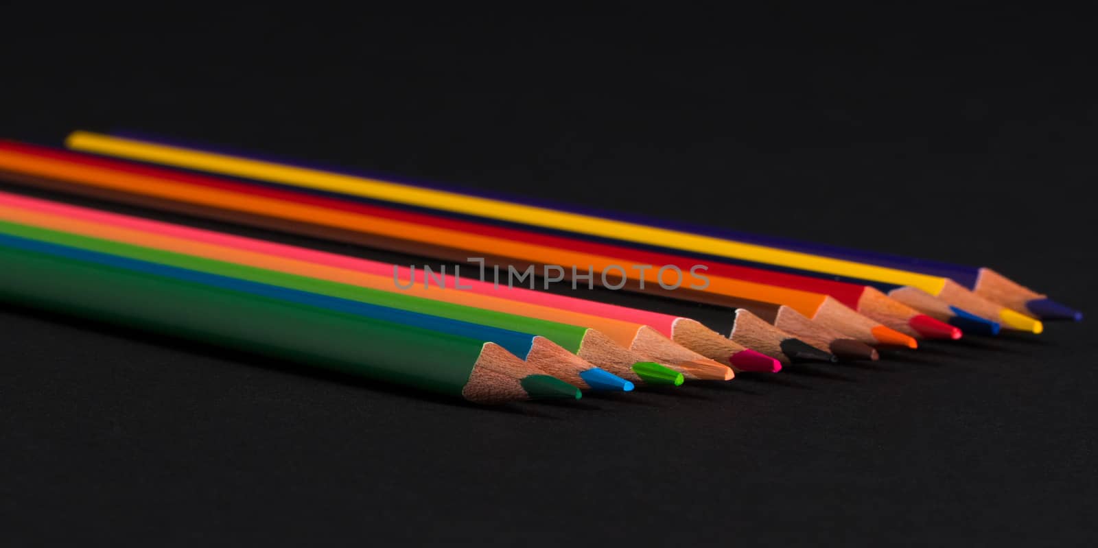 set of colored pencils on a black background isolated. back to school