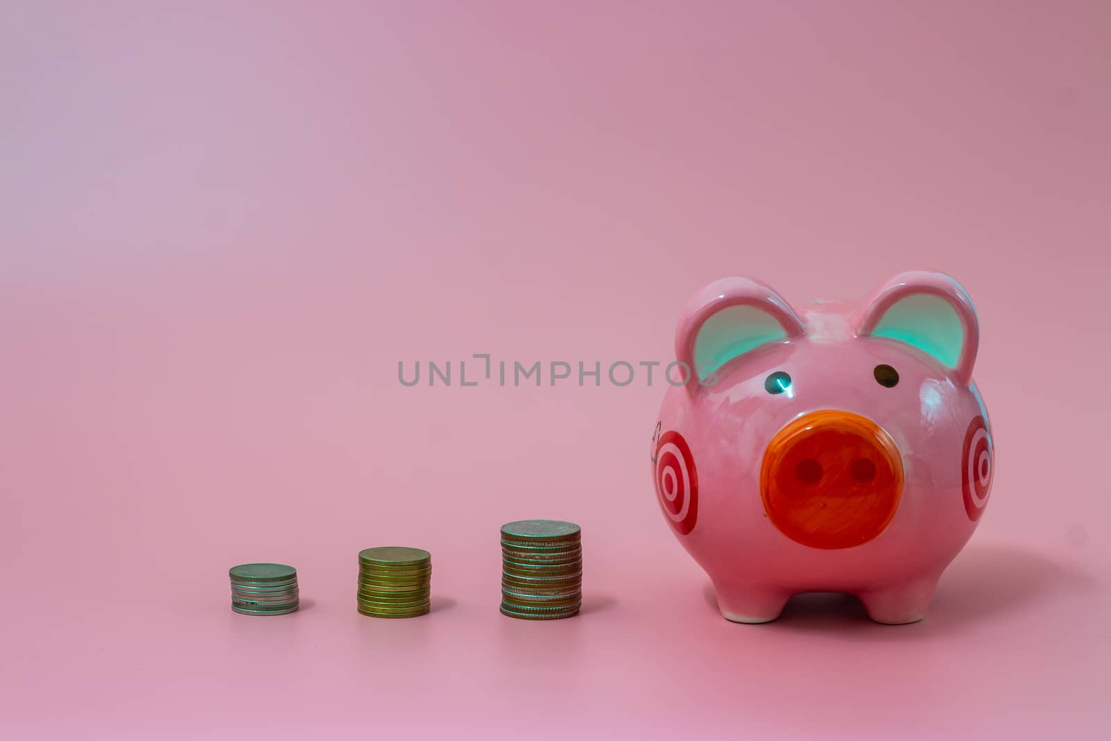 Pink piggy bank and coins on pastel pink background, Financial concepts