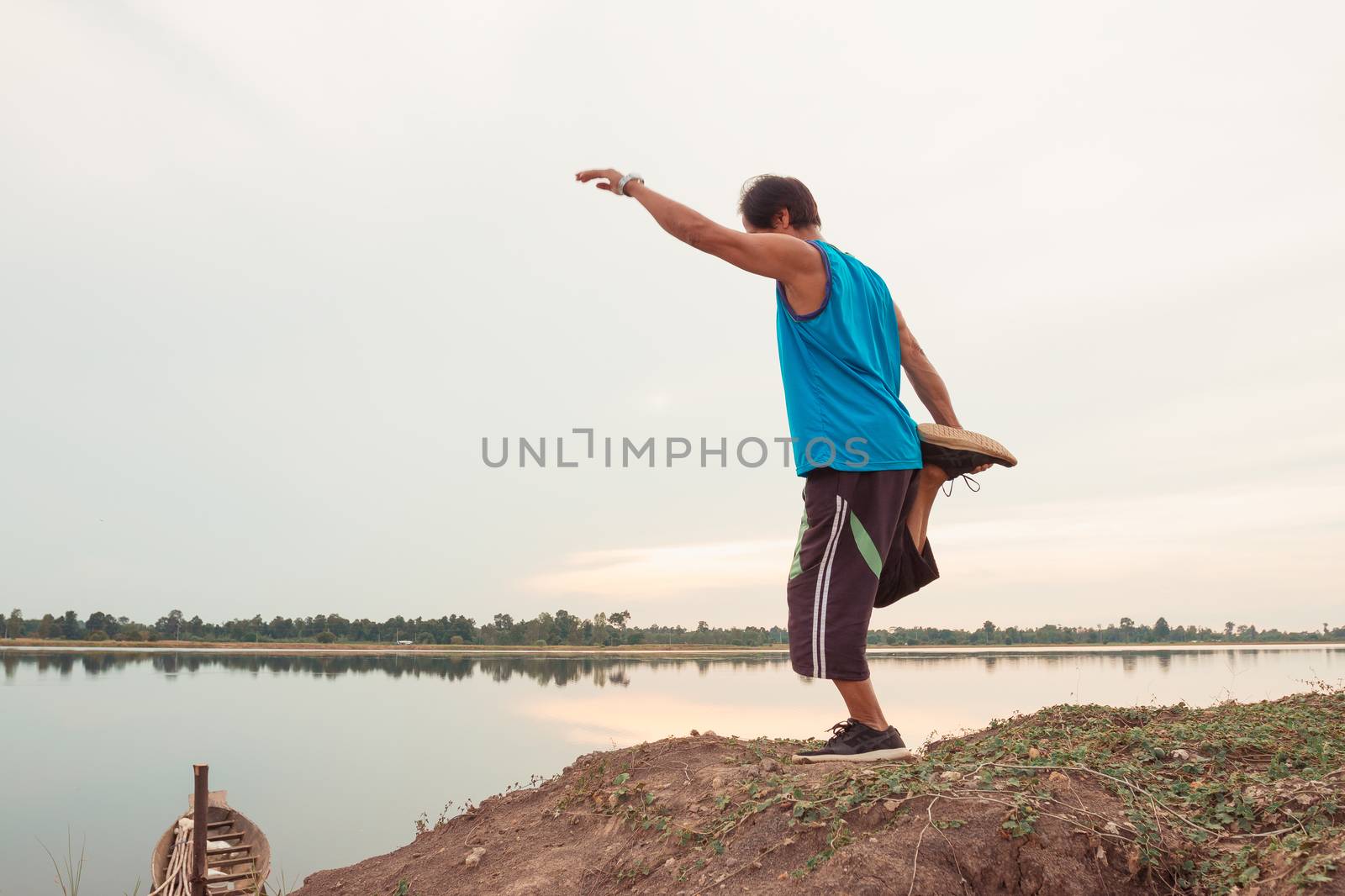 Old men exercise for health by jogging at sunset by the edge of the natural lake, health concept.