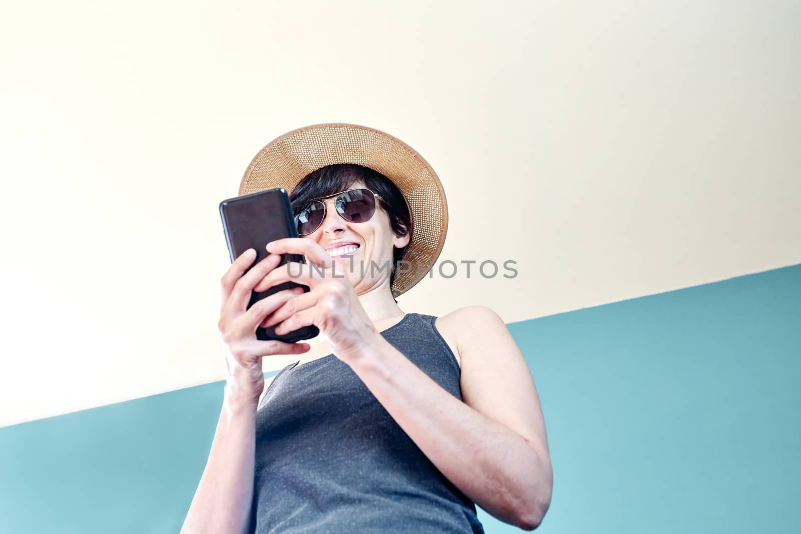 Woman in striped shirt and straw hat using mobile phone by Daniel_Mato