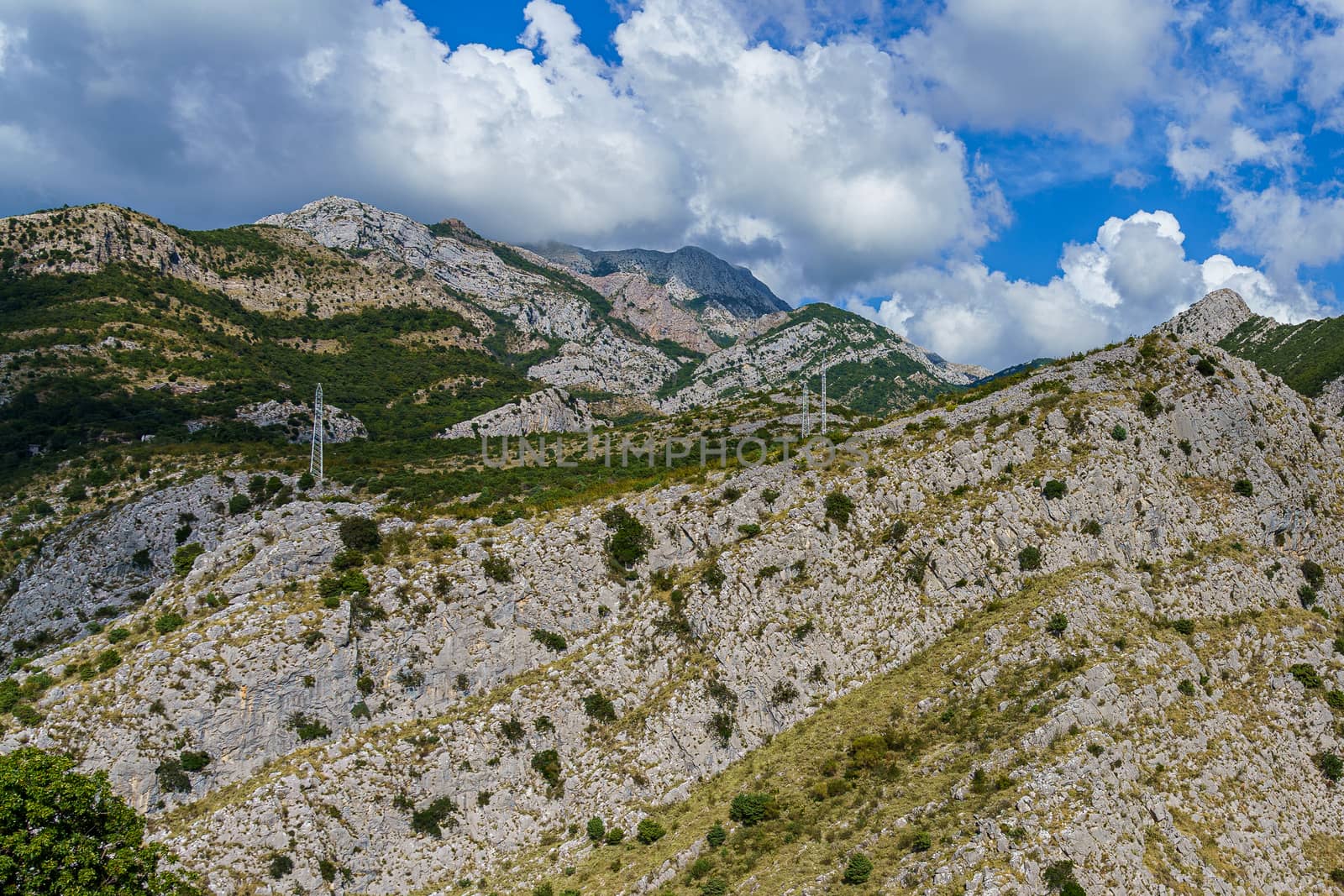 peaks and slopes of mountains covered with vegetation against a blue sky with clouds