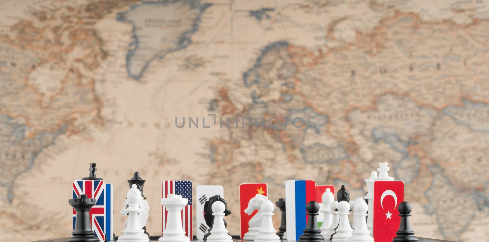 Country flag symbols on the chessboard with figures on the background of the political map of the world. Conceptual photo of a political game.