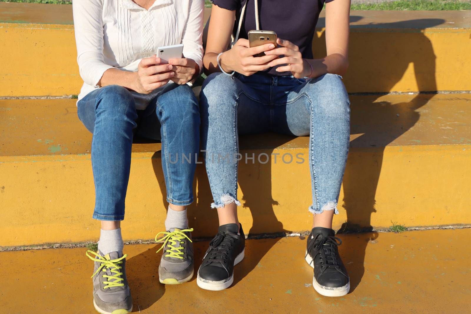 Two young girls watching smart mobile phones