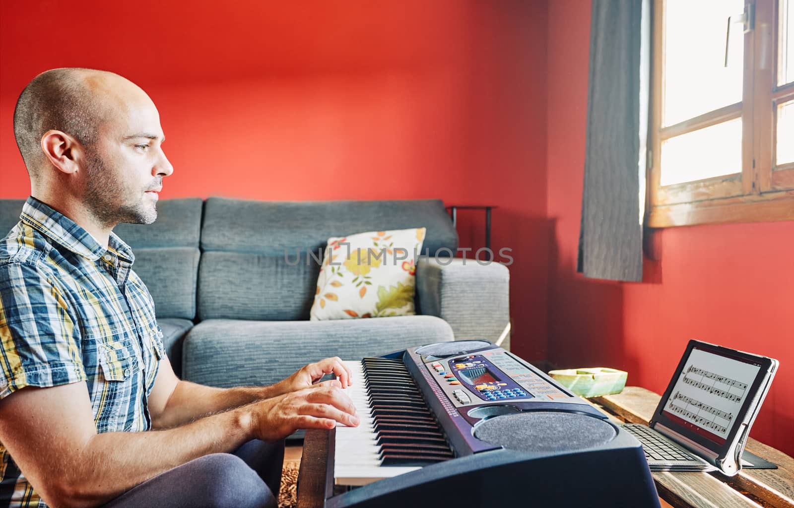 Man playing piano while taking online lessons at home.