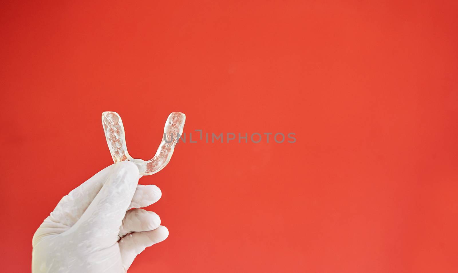 Invisible bracelets on a red background held in one hand by a latex glove
