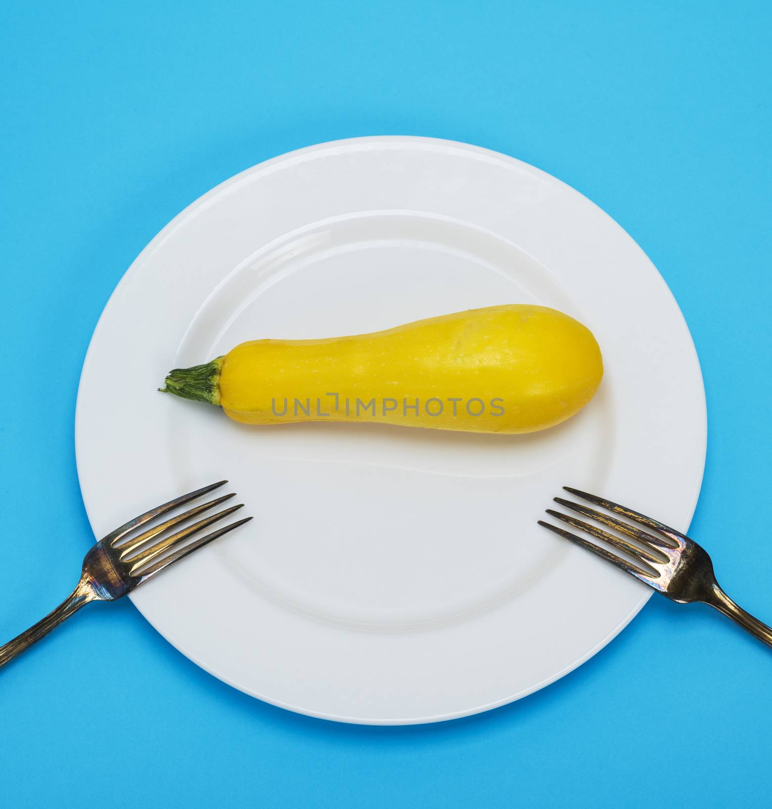 raw yellow squash in a white ceramic plate and iron fork, healthy lifestyle