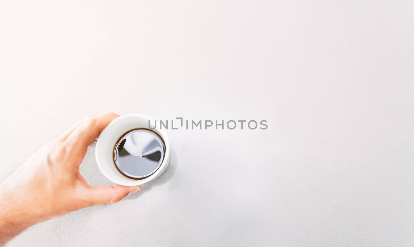 Hand holding a cup of coffee on a grey table