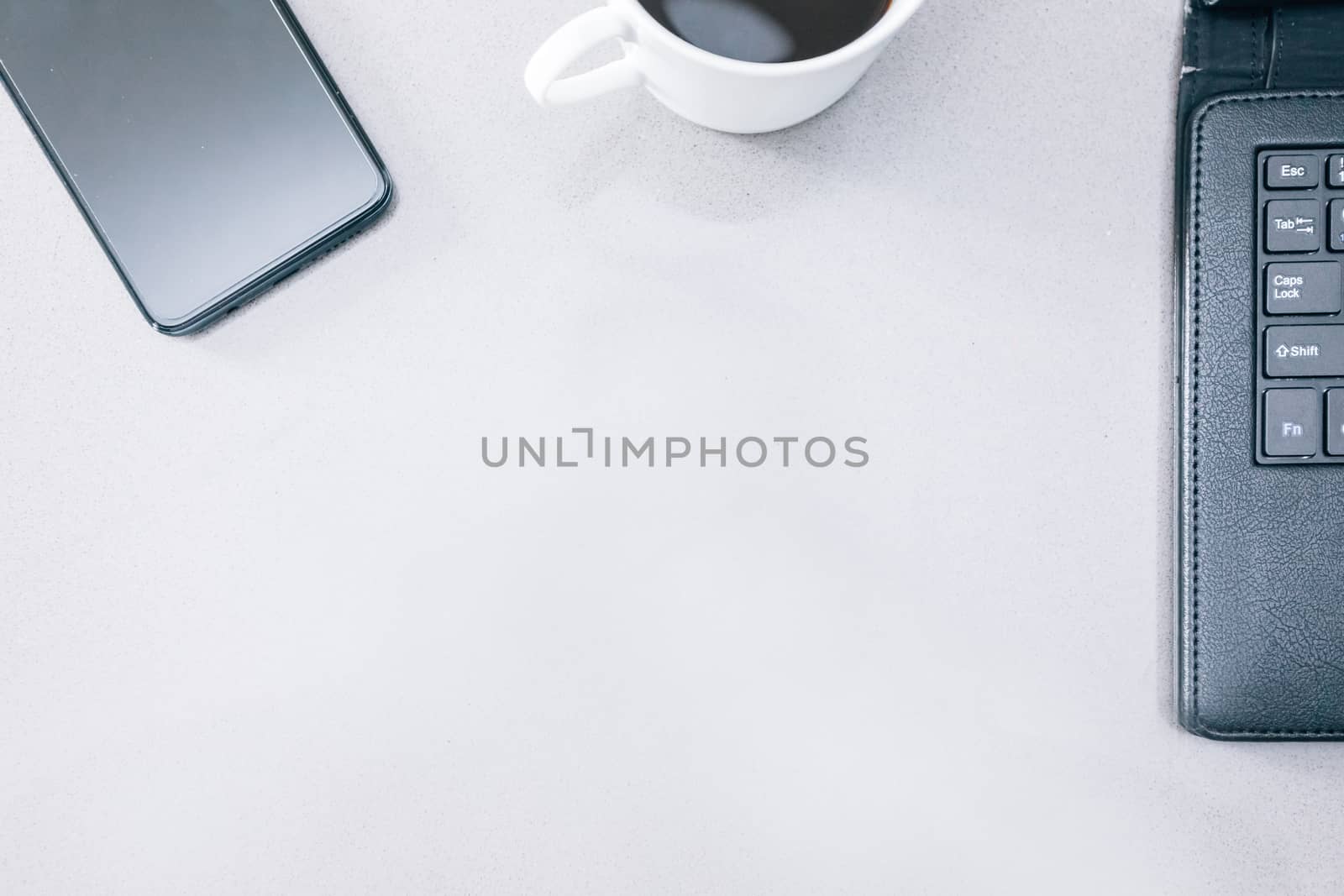 Grey table with a mobile phone, a tablet and a cup of coffee with some copy space