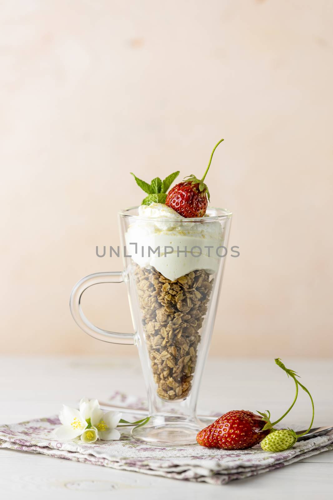 Glass of healthy breakfast with granola and greek yogurt close up. Sweet homemade yogurt with ripe fresh strawberries in a jar.