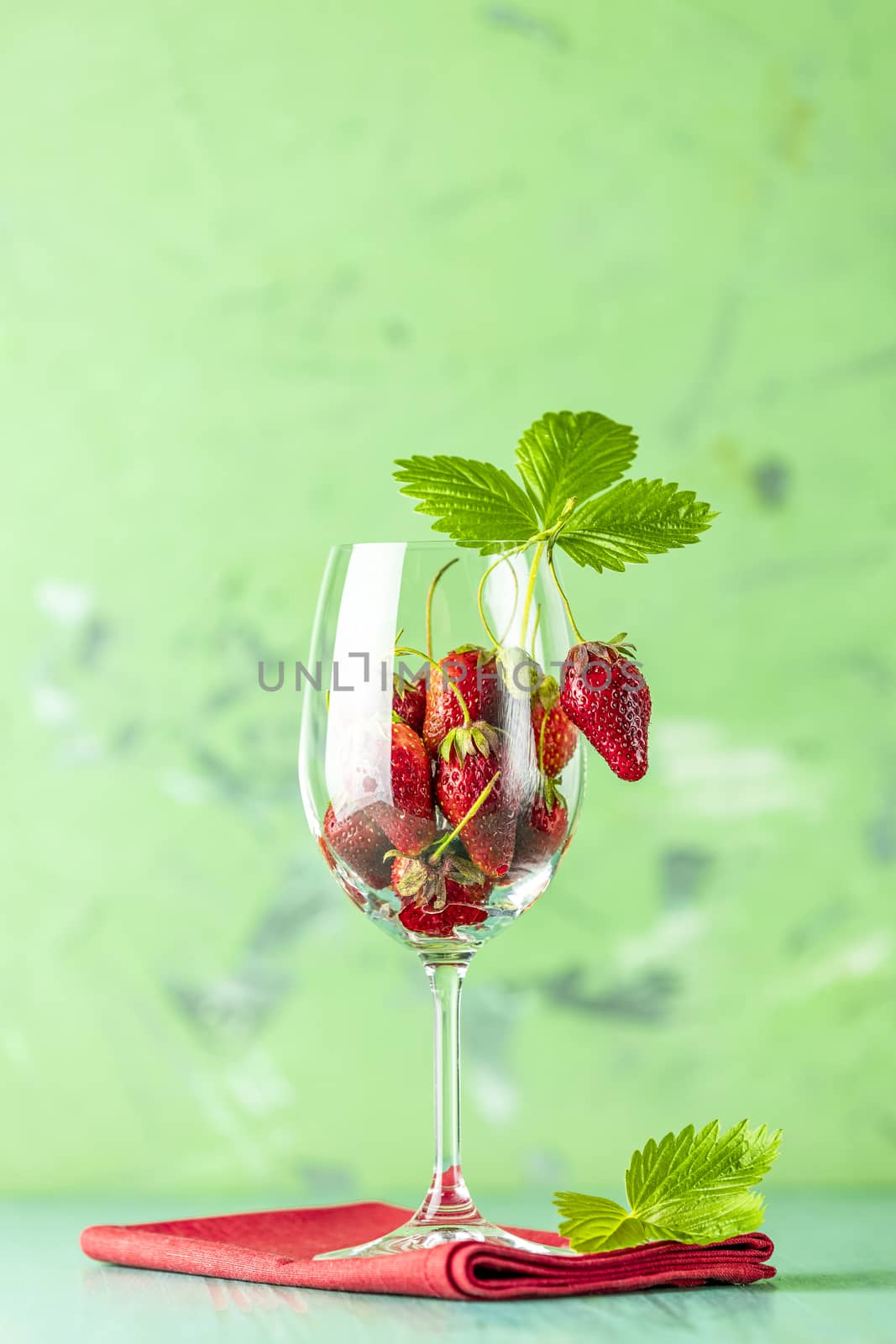 Fresh ripe raw strawberry with green leaves in the wine glass on by ArtSvitlyna