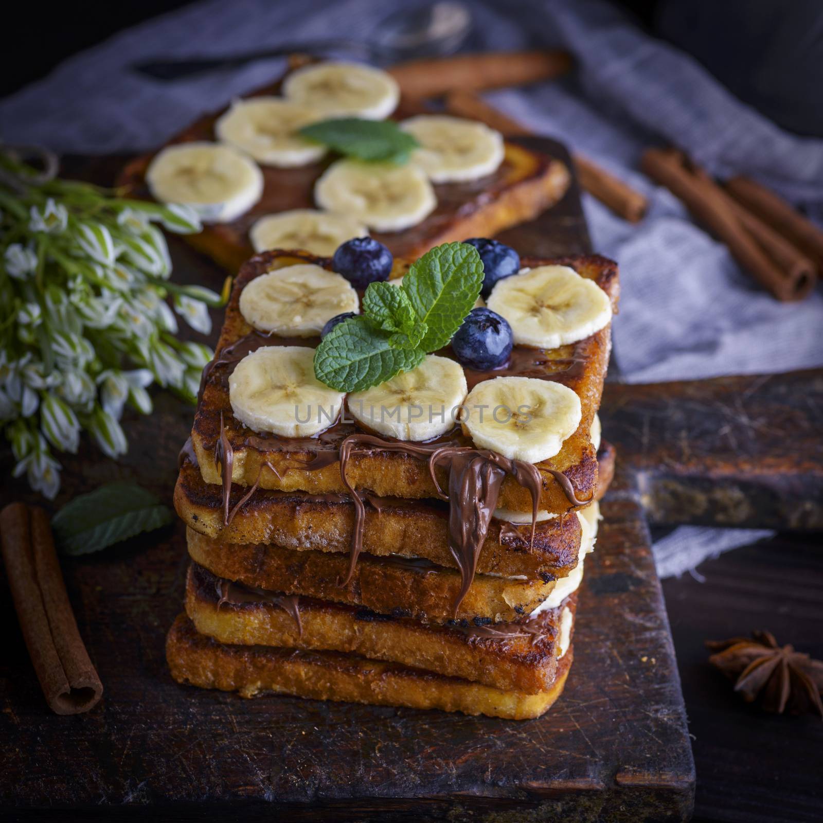 a pile of square fried bread slices with chocolate and banana  by ndanko
