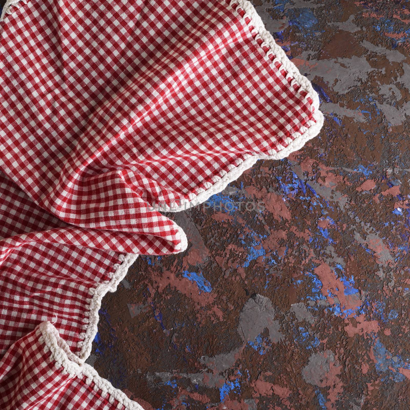 kitchen textile napkin in a red and white cell on a brown textured surface, copy space