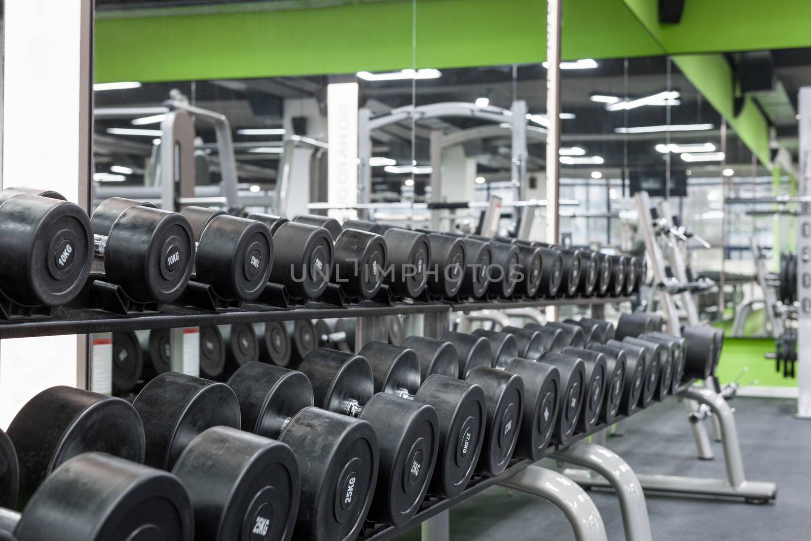 close up black sport dumbbells lie in a row on a stand