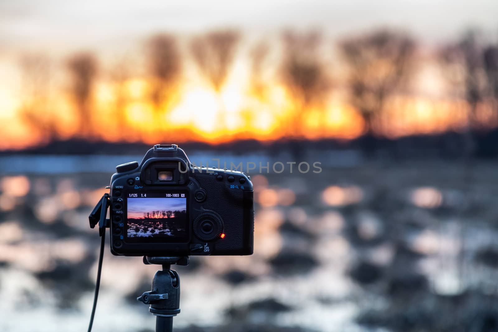 The camera takes a landscape photo on a tripod