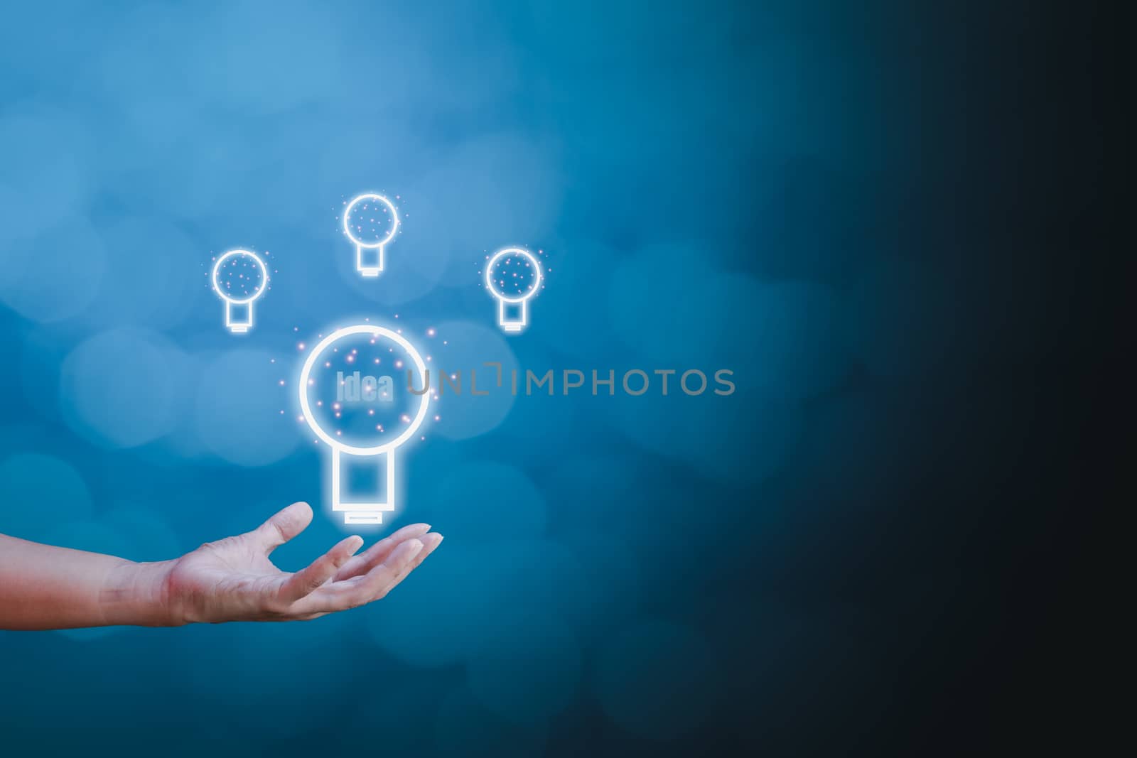 Inspiration, idea, and creative concept. Businessman holding light bulb sign on hand on blue bokeh background with copy space for text. 