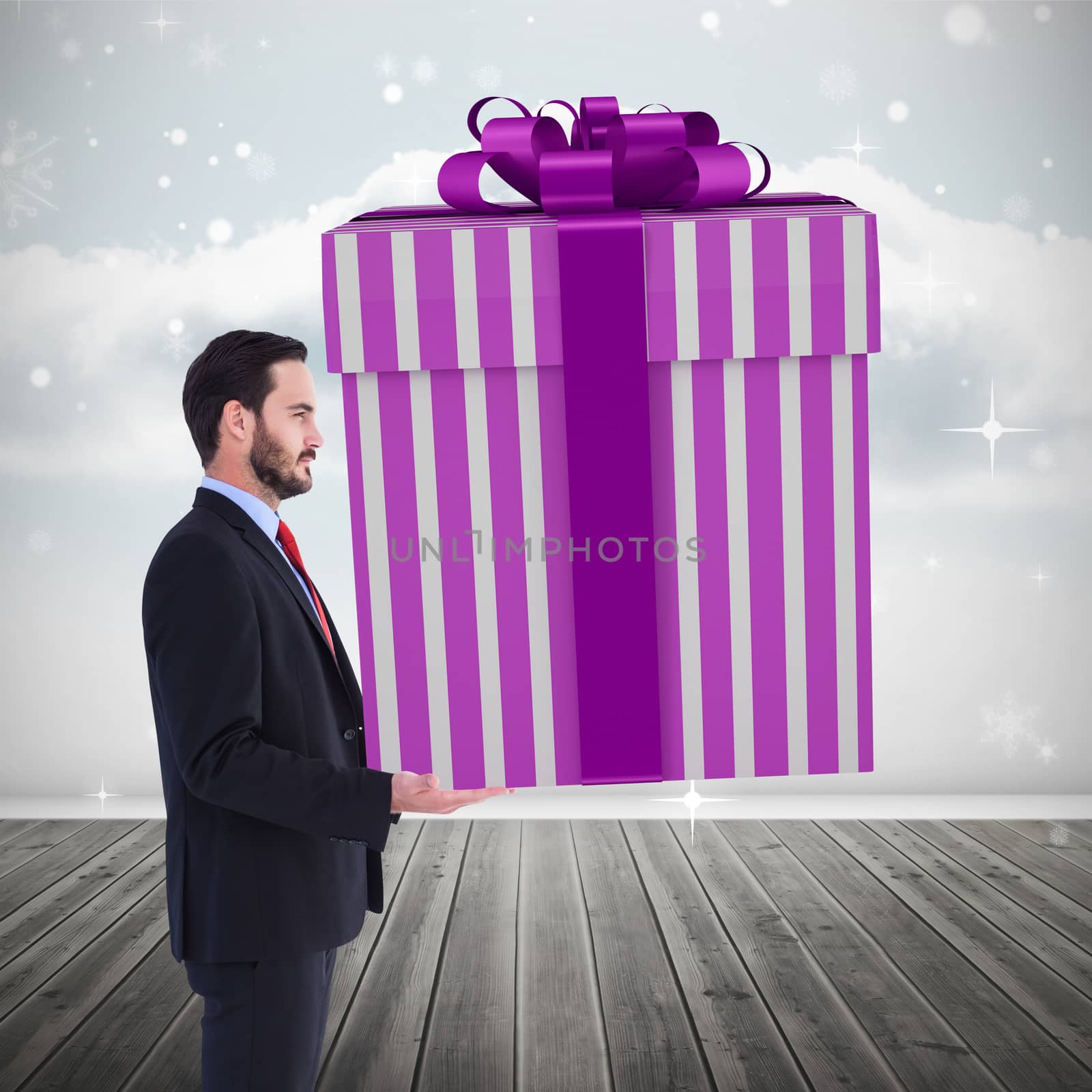 Stylish man with giant gift against clouds in a room