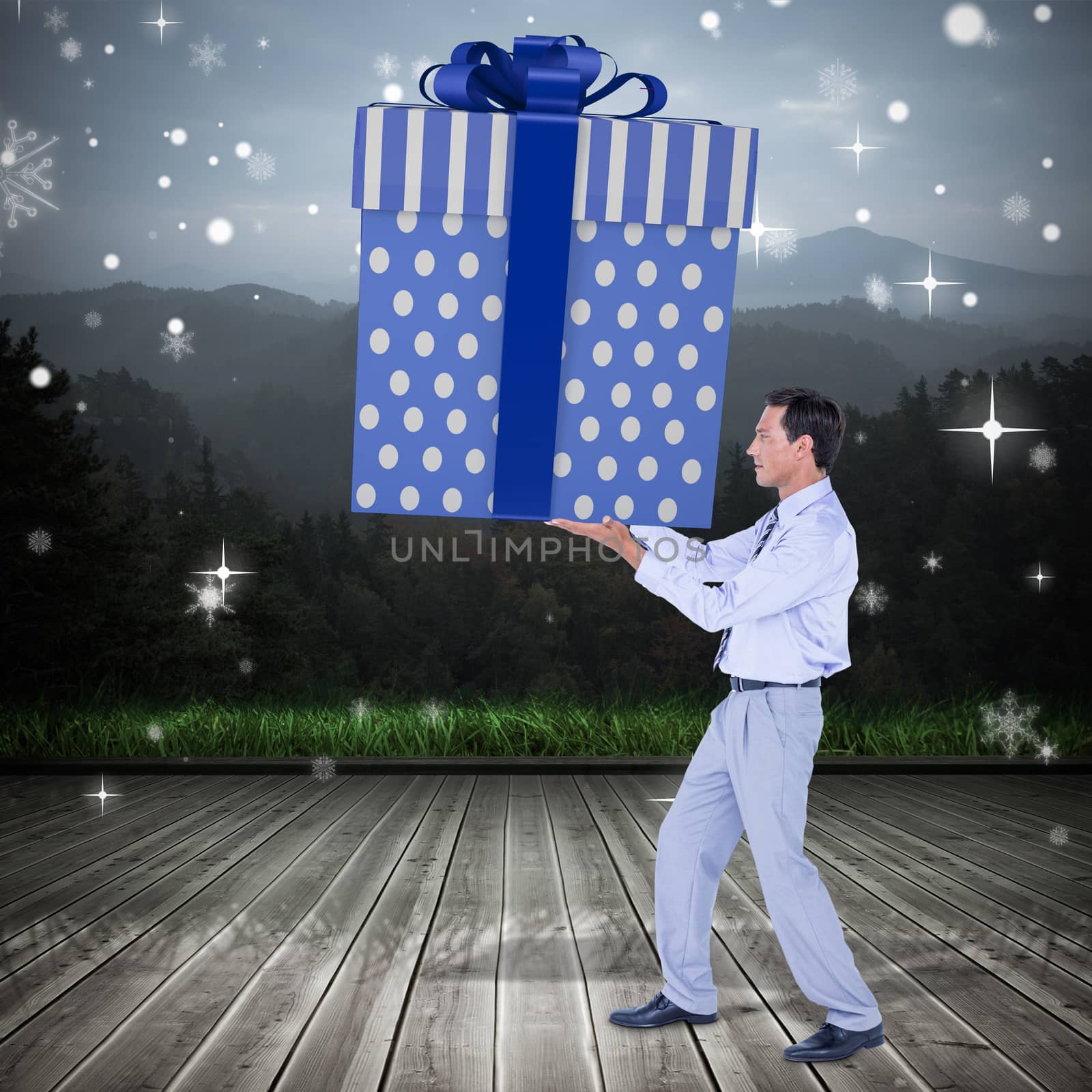 Stylish man with giant gift against wooden planks against mountains