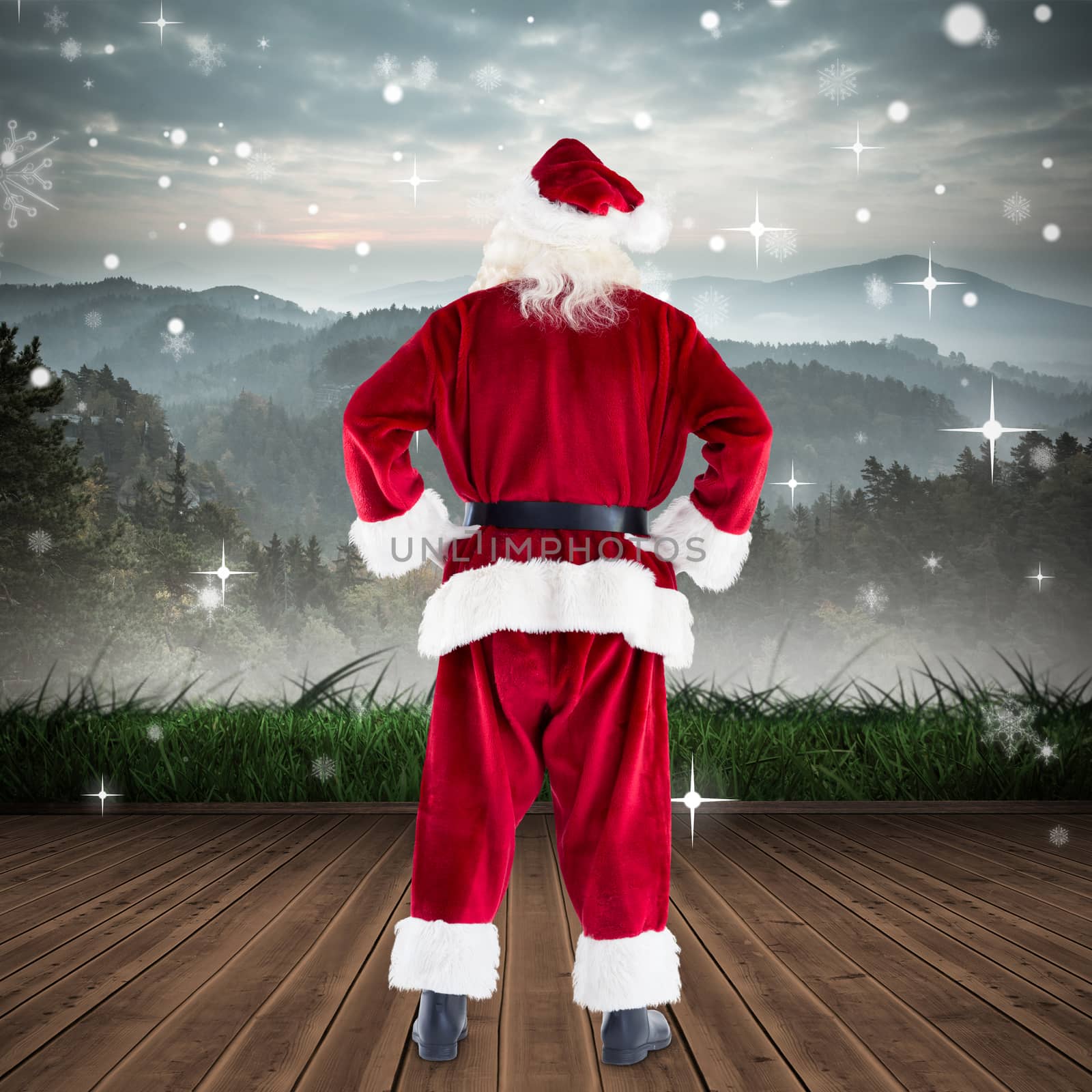 Santa standing with hands on hips against mountain range beyond wooden floor