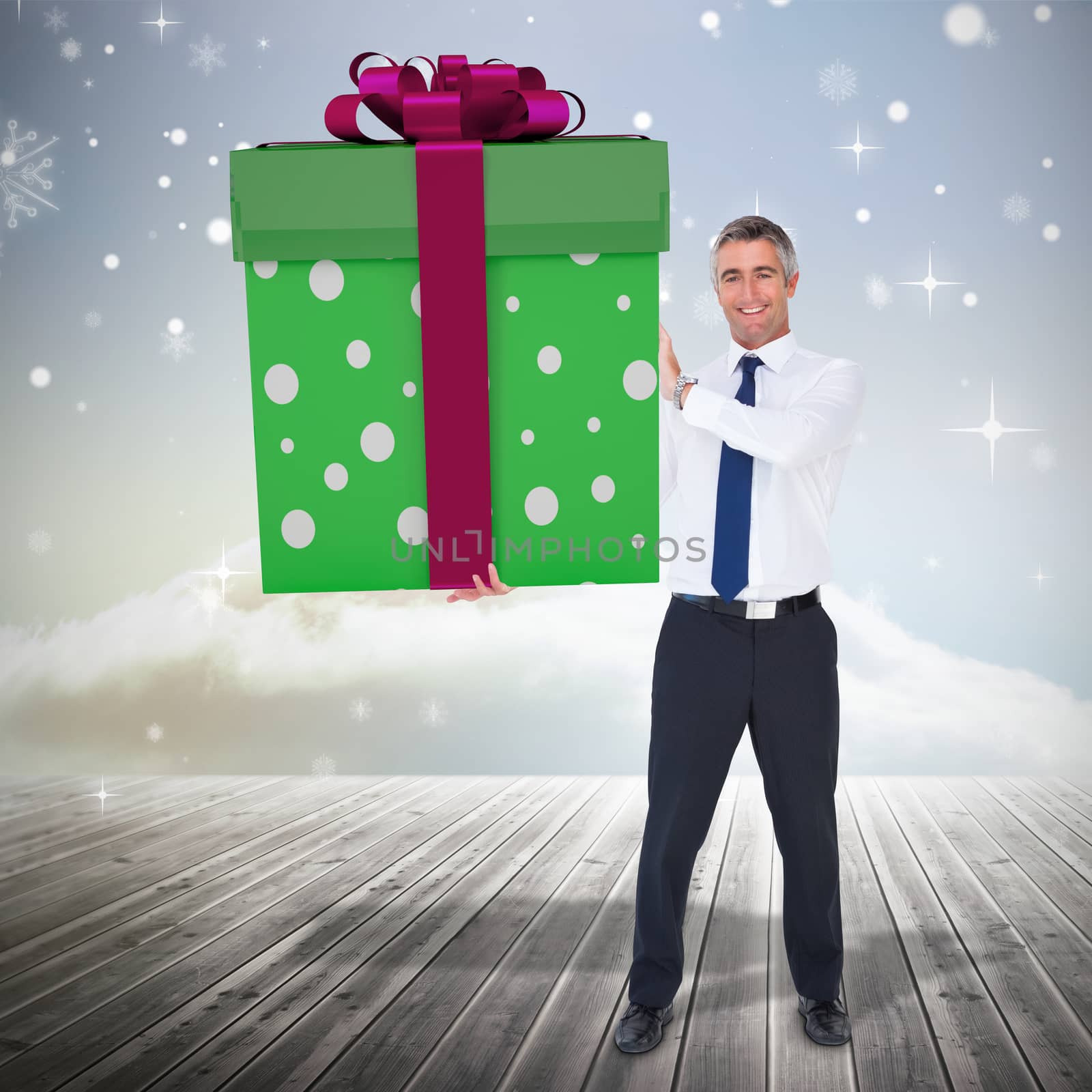 Stylish man with giant gift against clouds on the horizon