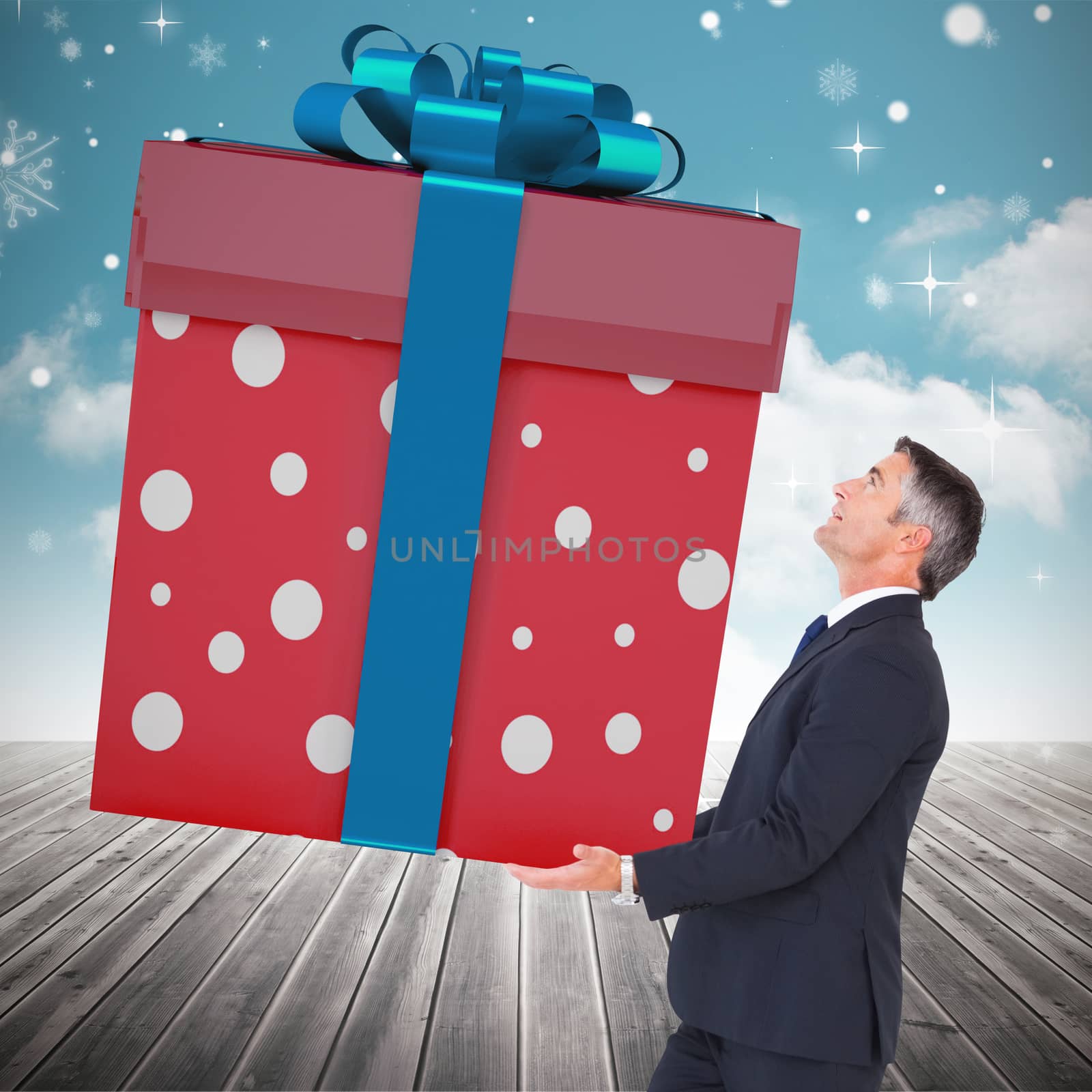 Stylish man with giant gift against cloudy sky background