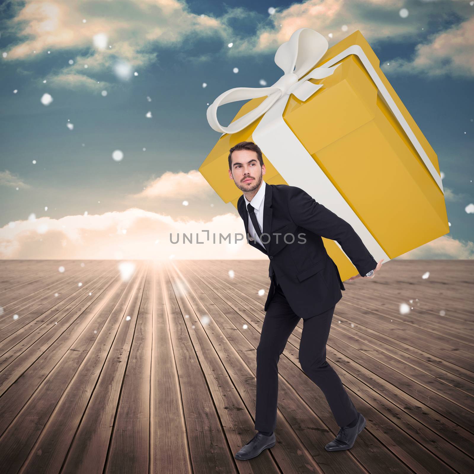 Stylish man with giant gift against wooden planks leading to blue sky