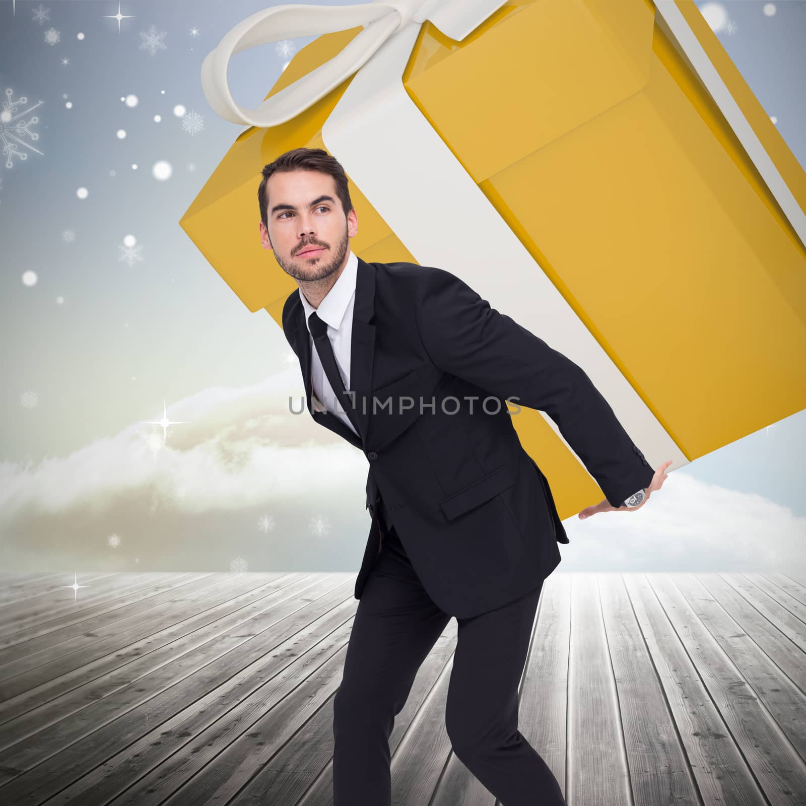 Stylish man with giant gift against clouds on the horizon