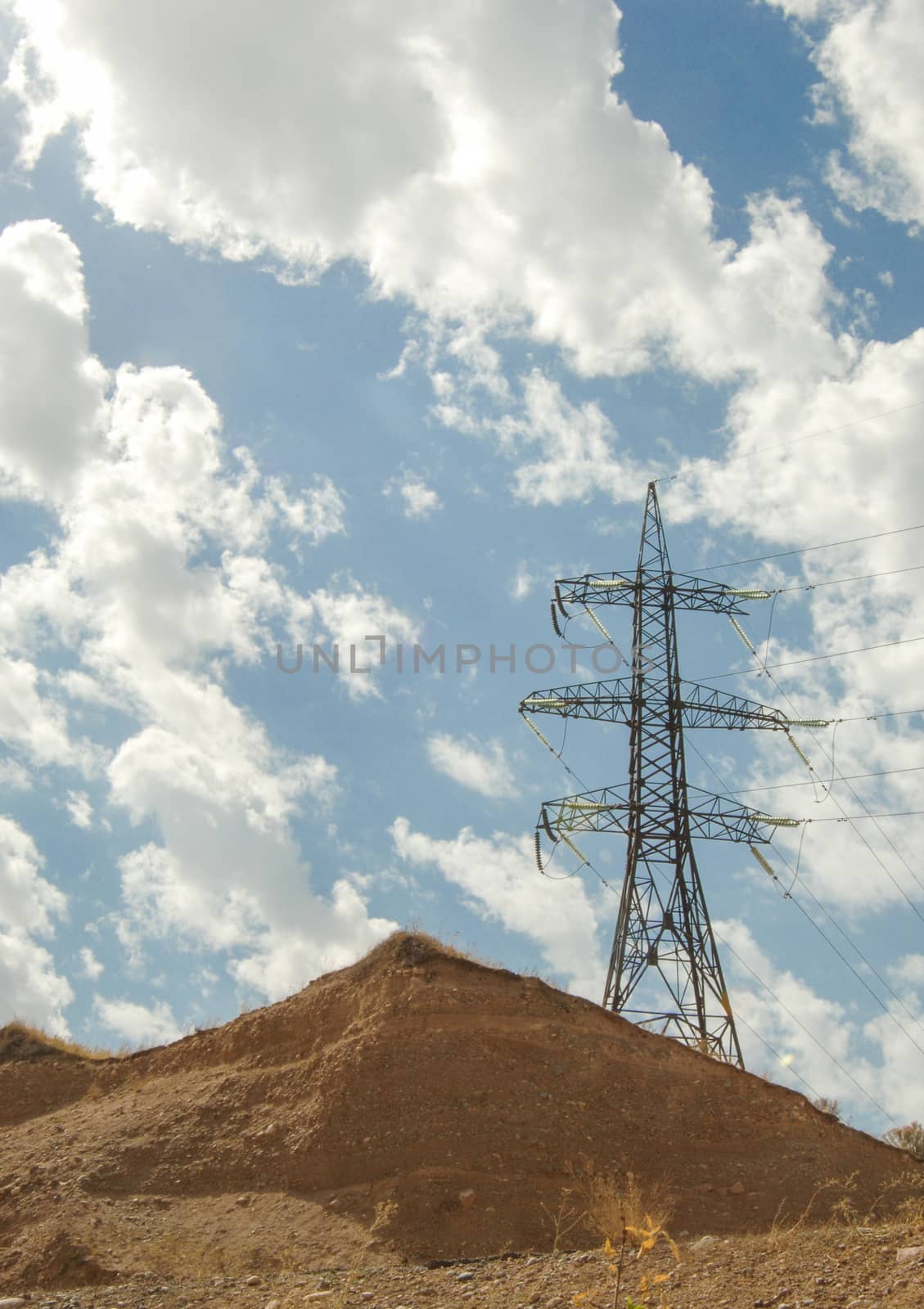 high voltage tower against the blue sky with clouds