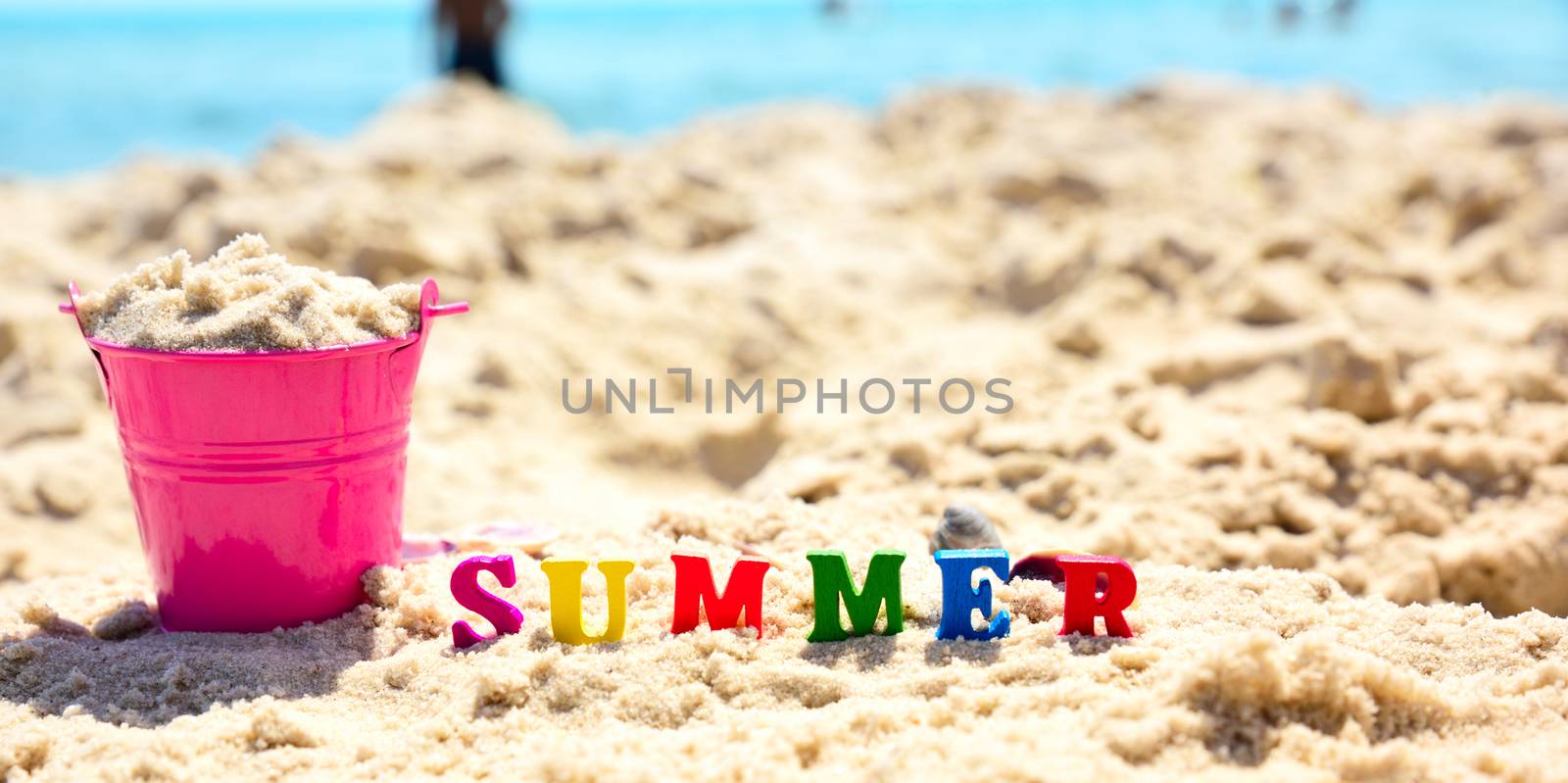 multicolored wooden letters in the word summer on sand, close up