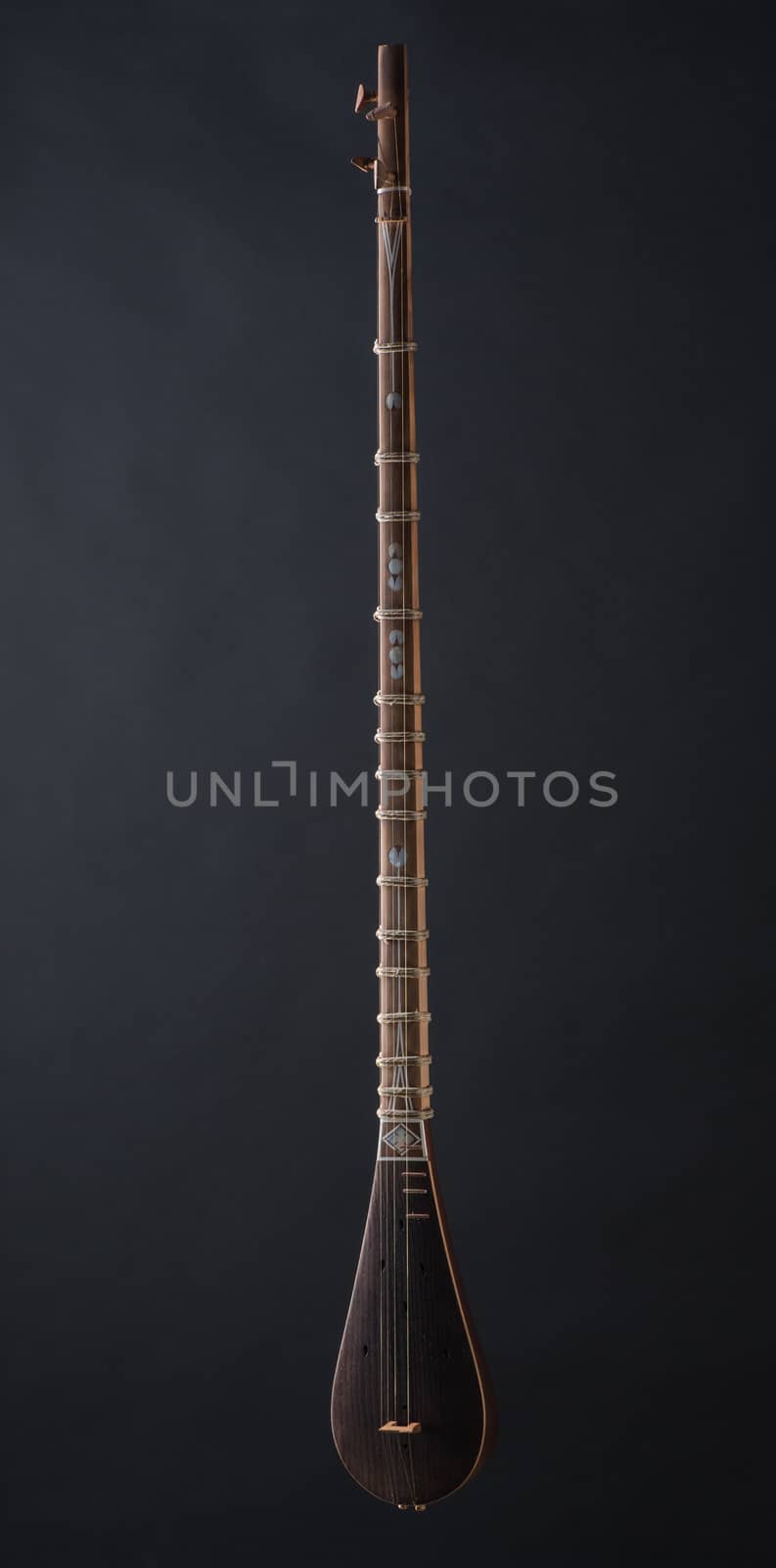 ancient Asian stringed musical instrument on black background with backlight