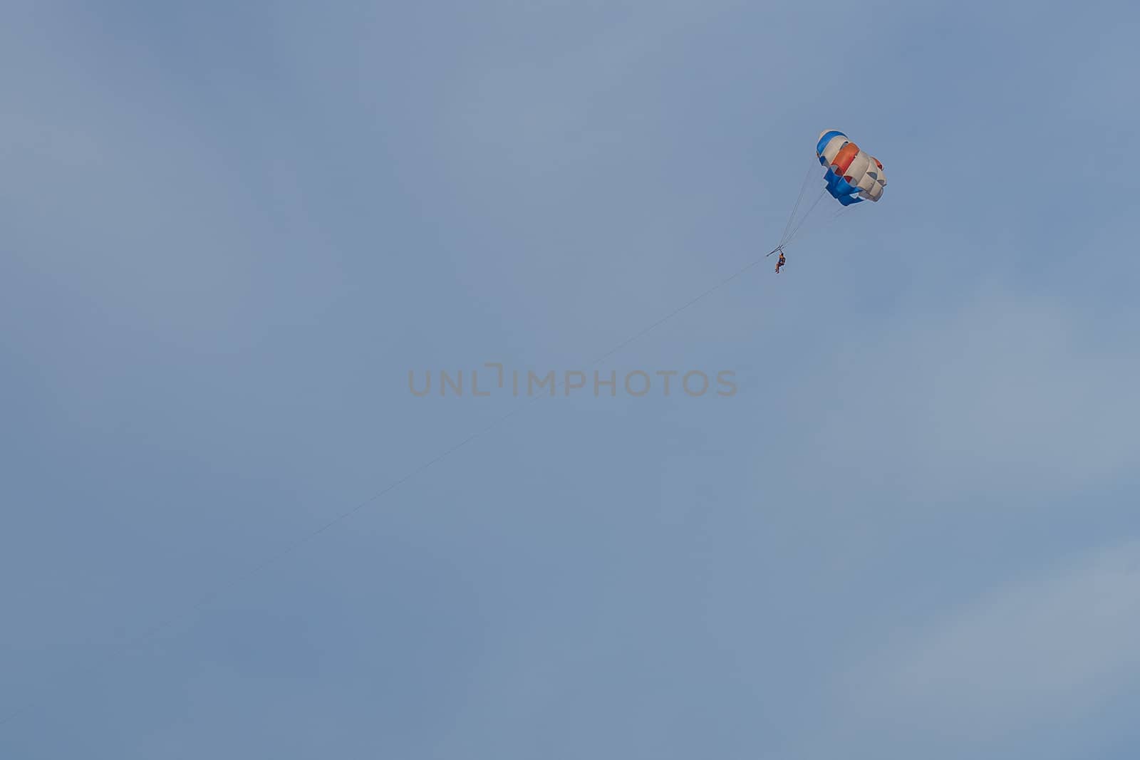 Parasailing. Man parachuting behind a boat against a blue sky