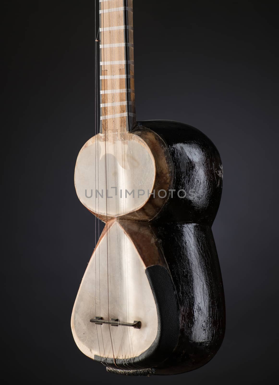 part ancient Asian stringed musical instrument on black background with backlight