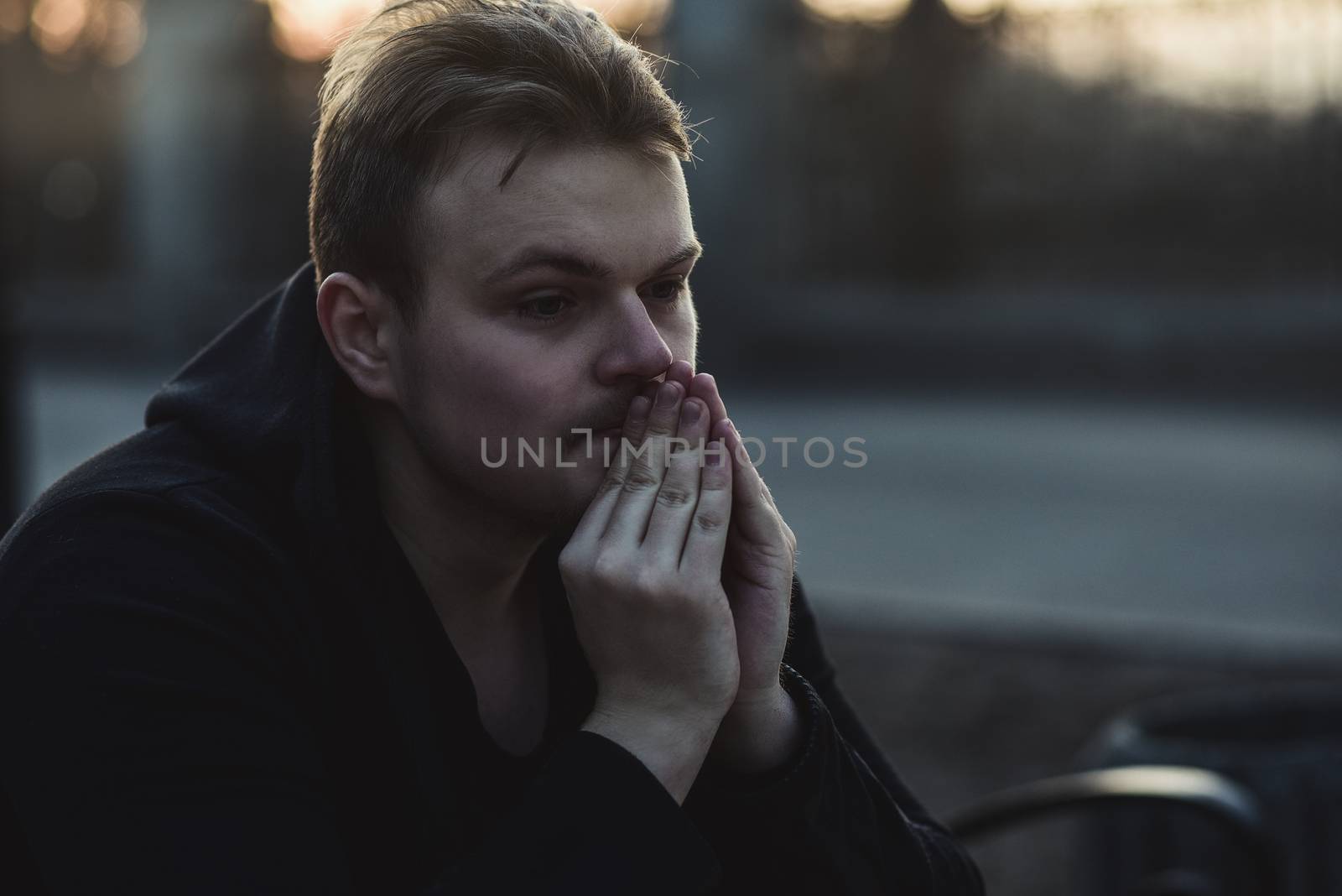Portrait of a sad, depressed man sitting alone at street