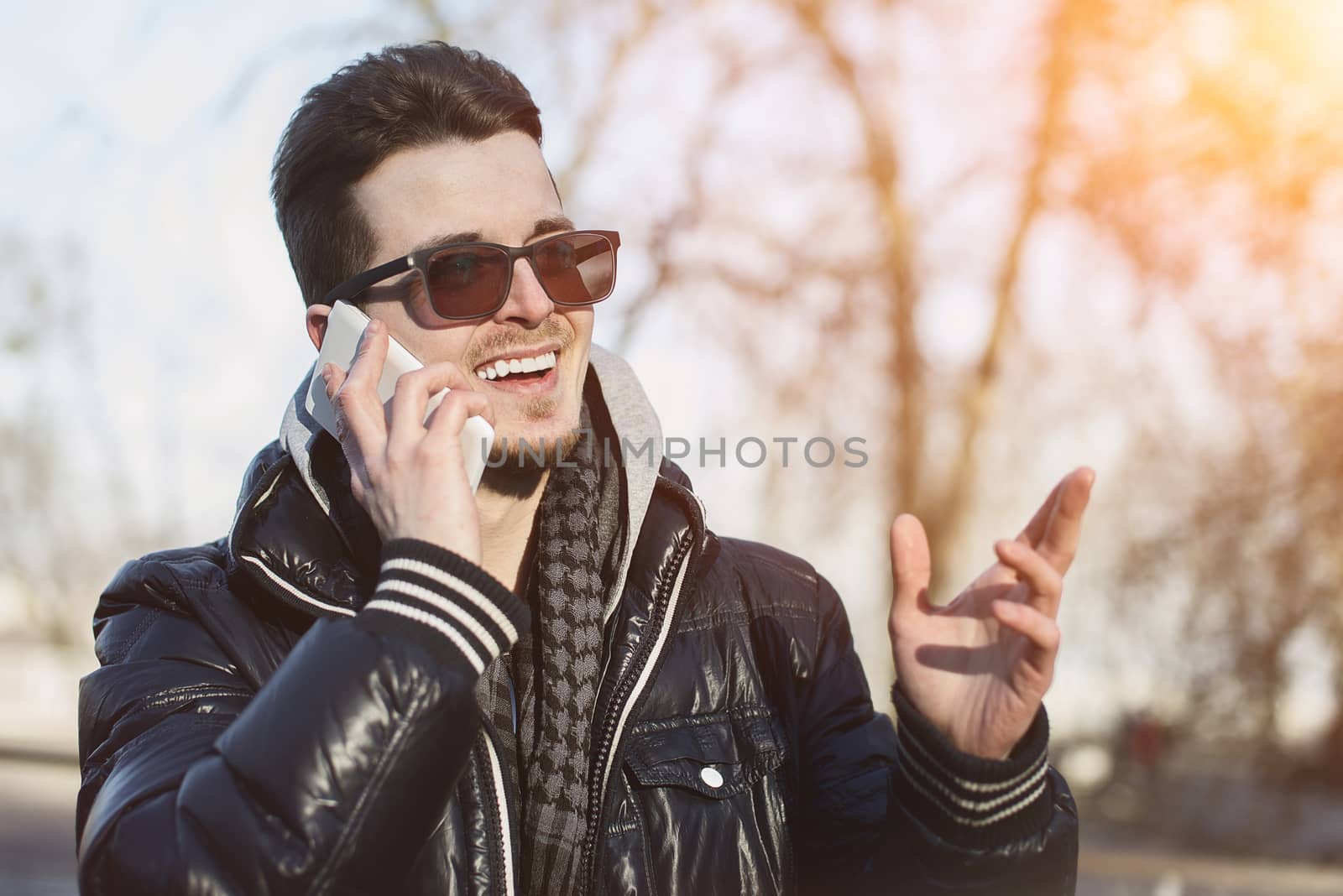 A Guy in a warm jacket with a smartphone in his hands, a sunny day.
