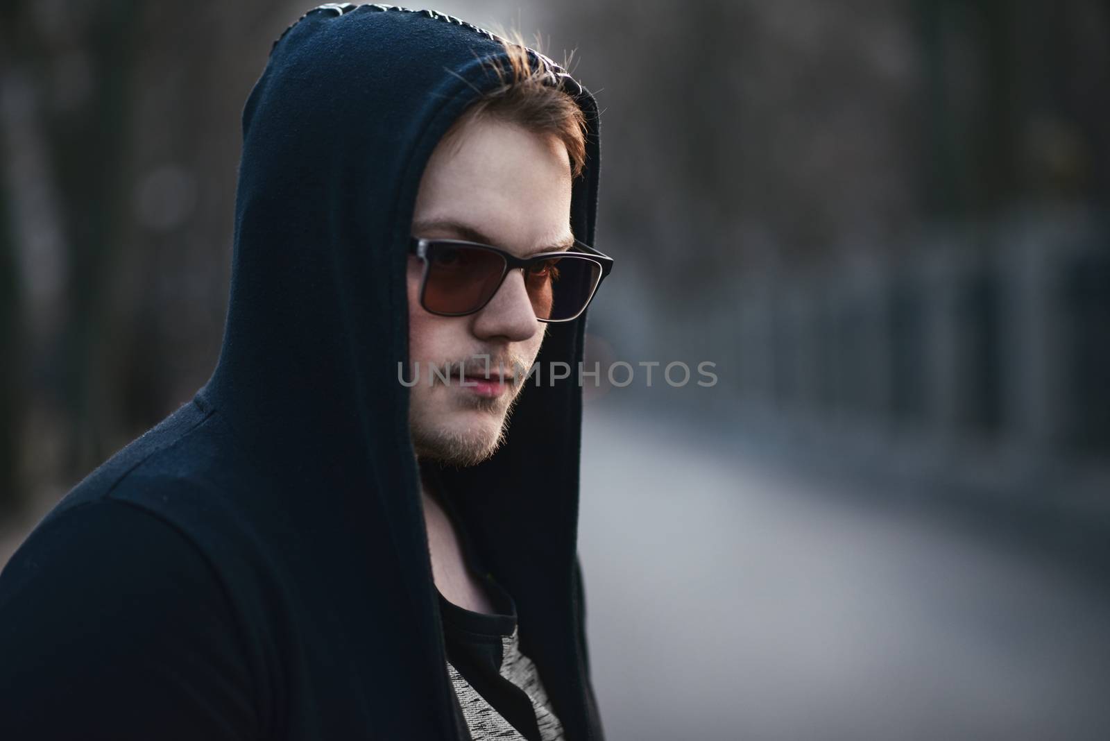 Portrait of fashion man in a black sweater with a hood and sunglasses