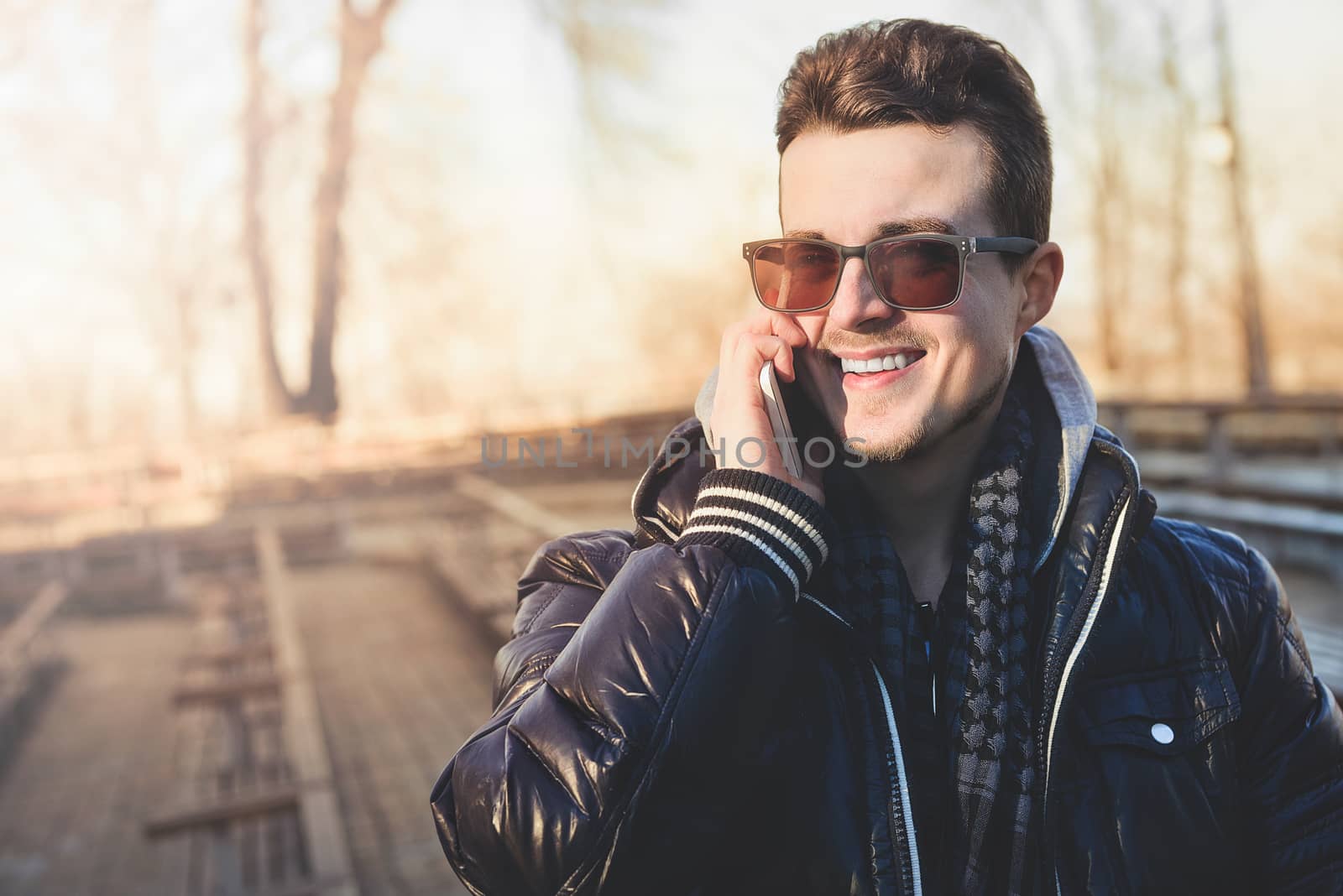 A Guy in a warm jacket with a smartphone in his hands, a sunny day.