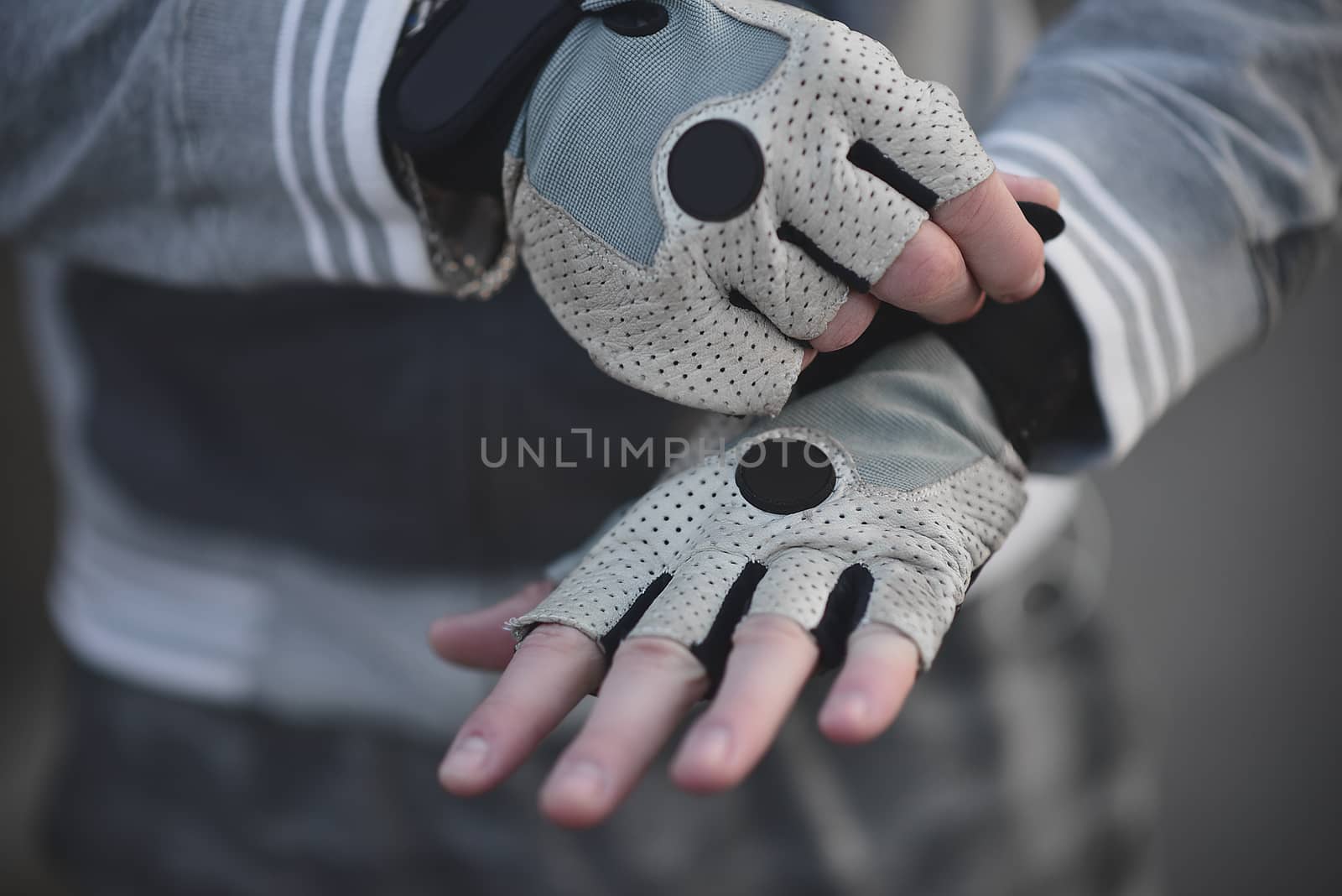 A Man on the street puts on his hands sports gloves and prepares for coaching.