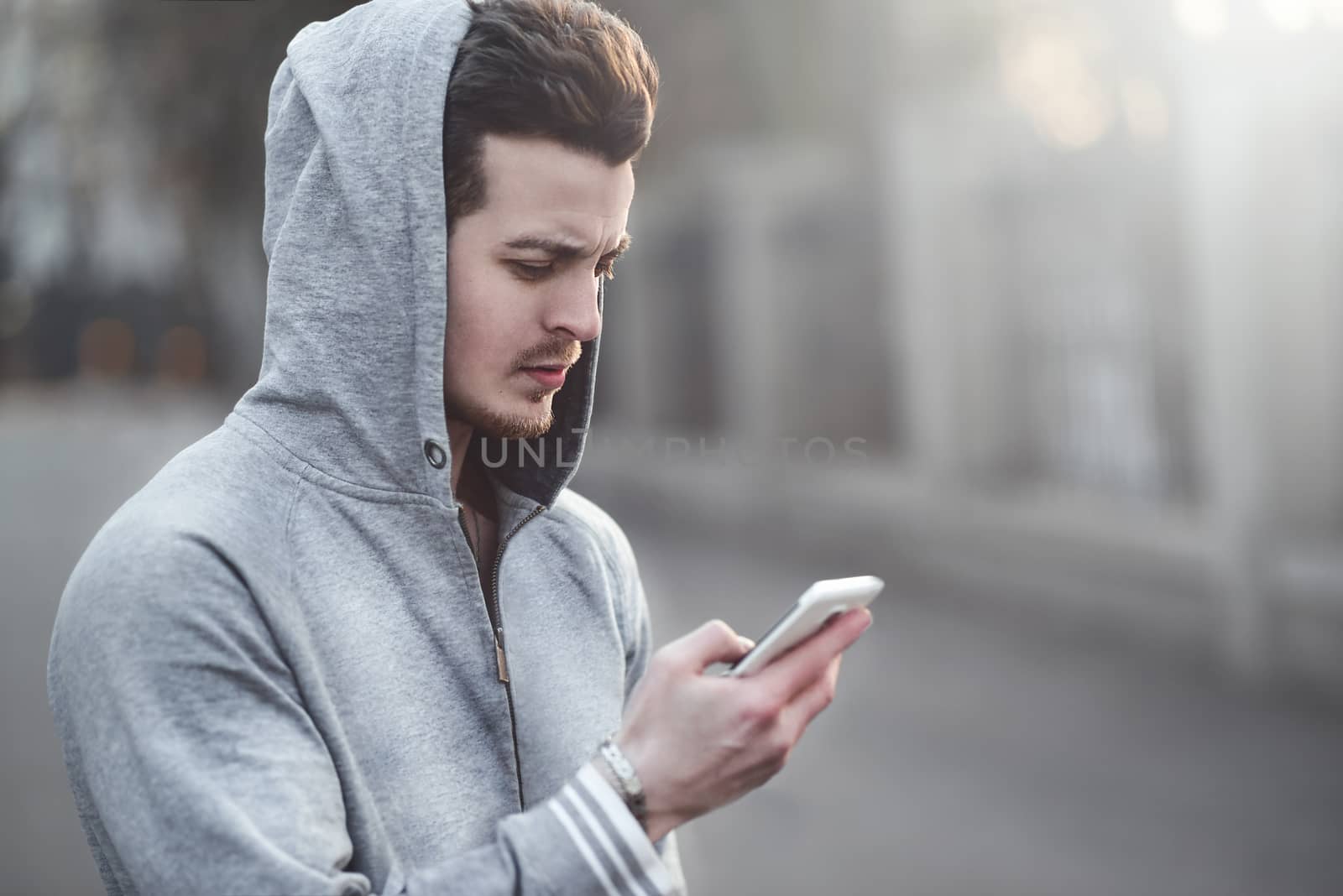 Happy teen boy walking on the street and using a smart phone.