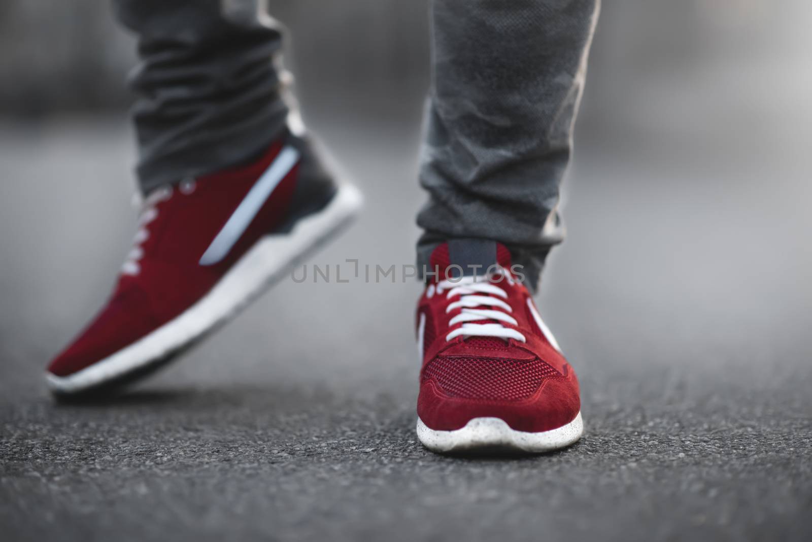 Sports red sneakers close-up on asphalt. Legs and shoes from the lower angle