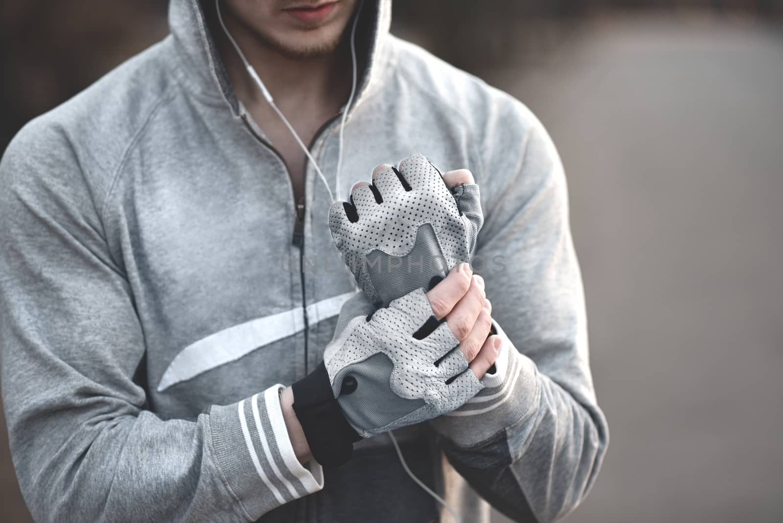 A Man on the street puts on his hands sports gloves and prepares for coaching.