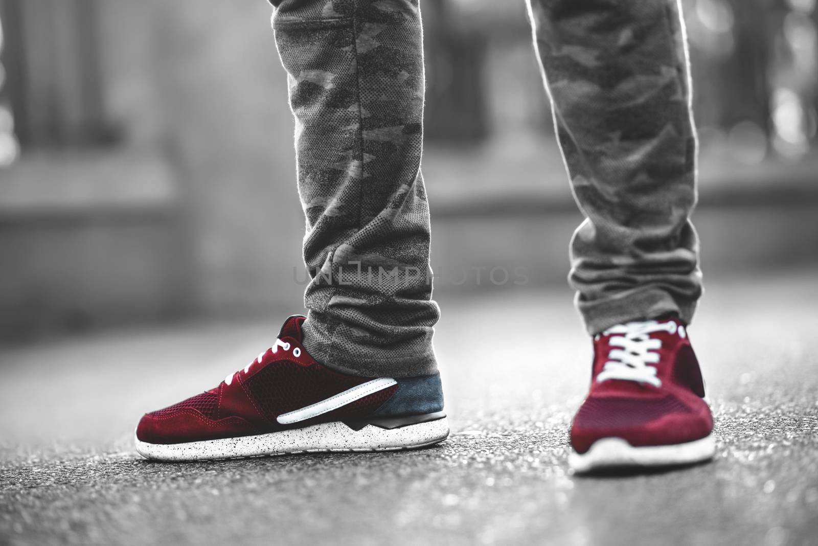 Sports red sneakers close-up on asphalt. Legs and shoes from the lower angle