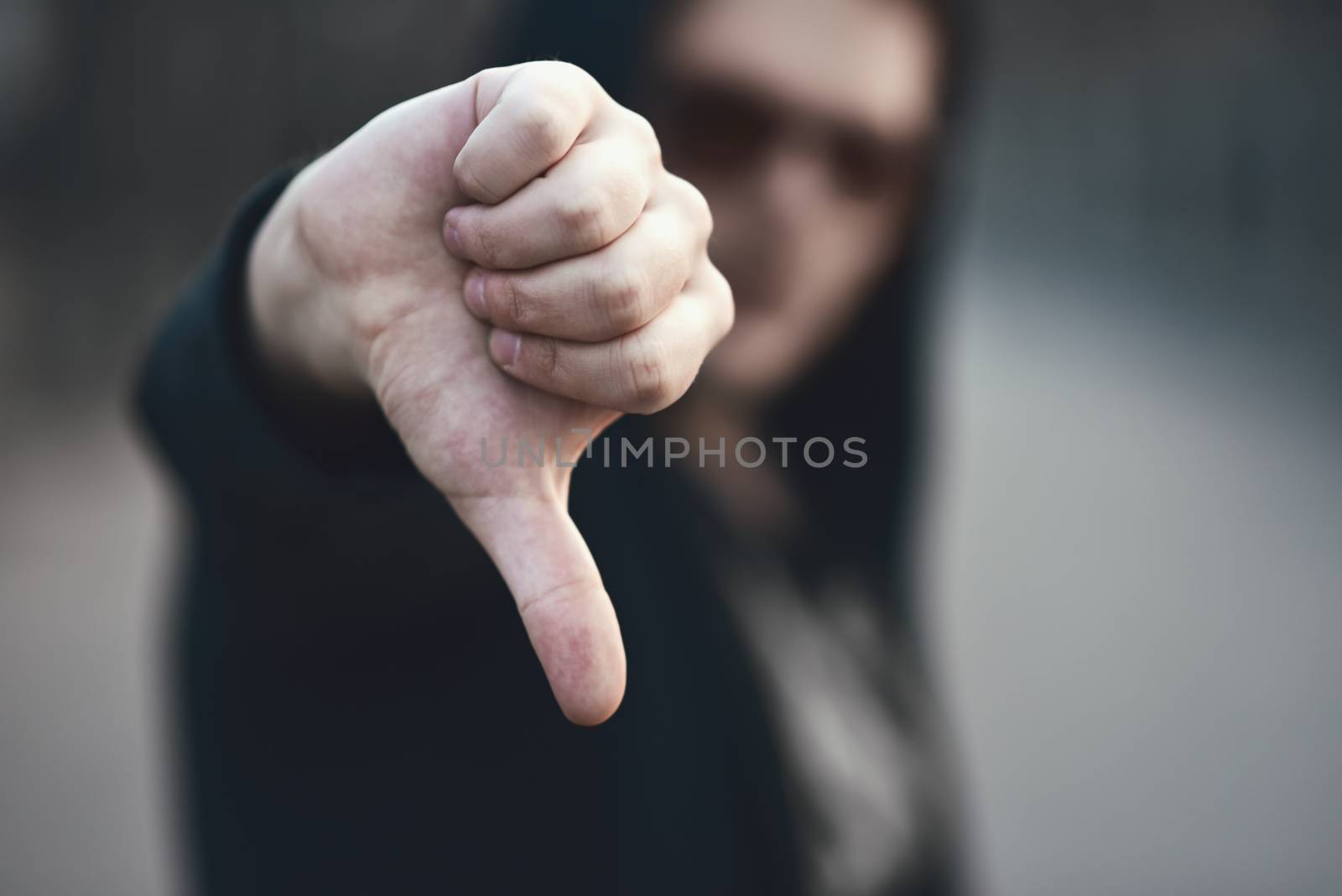 Portrait of fashion man in a black sweater with a hood and sunglasses, hand gestures.