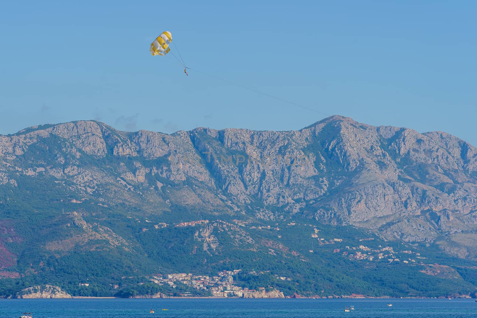 Parasailing. Man parachuting behind a boat against a blue sky
