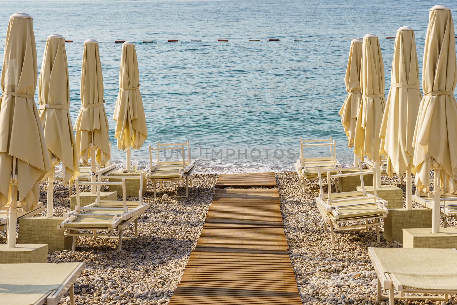 Folded beach umbrellas on the background of the sea. The beach is getting ready to open.