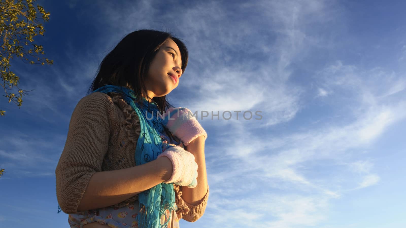 The girl stands in the first light of the day with a blue sky background, shooting in a low angle.