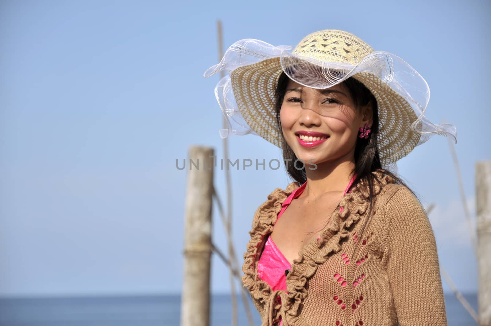 Portrait of a cute girl wearing a pink dress on a beautiful sunny summer day with a blurred sea background.