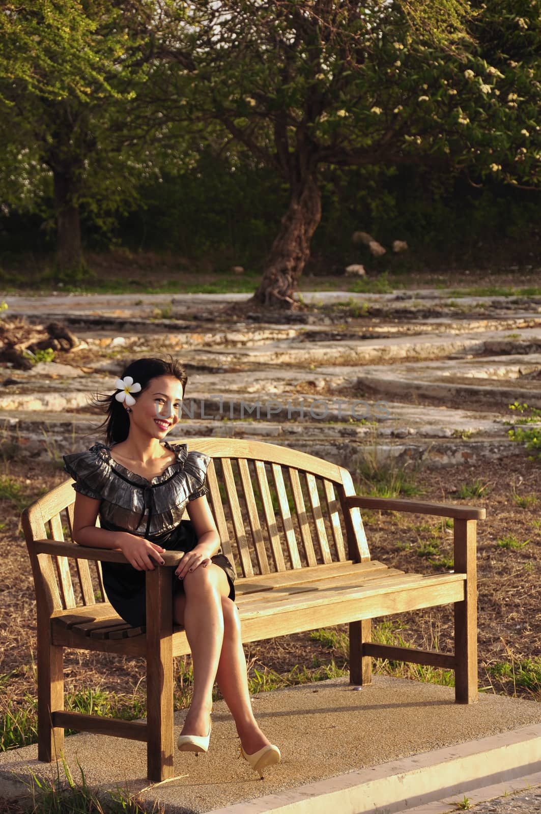 The image of a young woman in black sitting happily smiling on the table in the first light of a beautiful day.