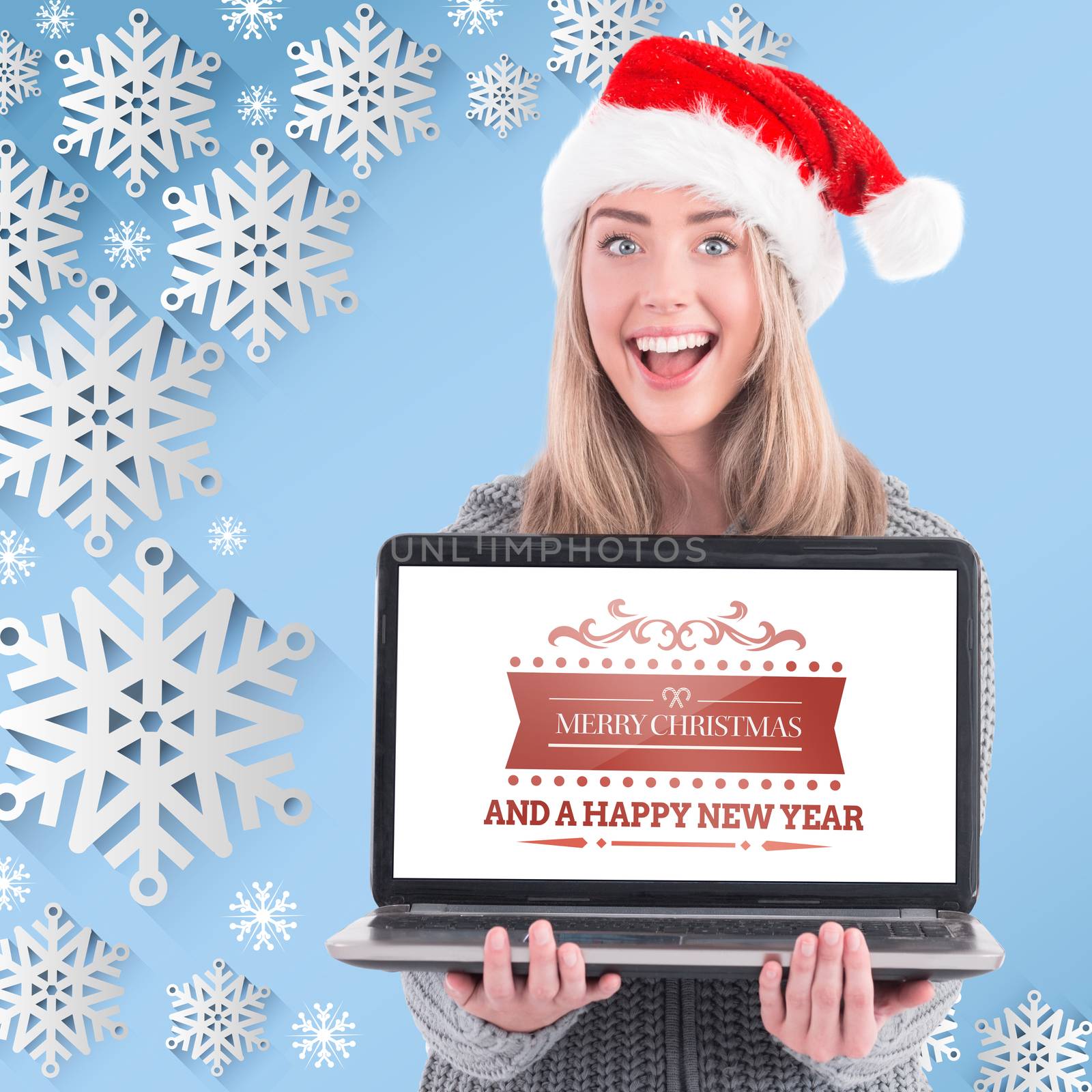 Festive blonde holding a laptop against snow flake frame design on blue