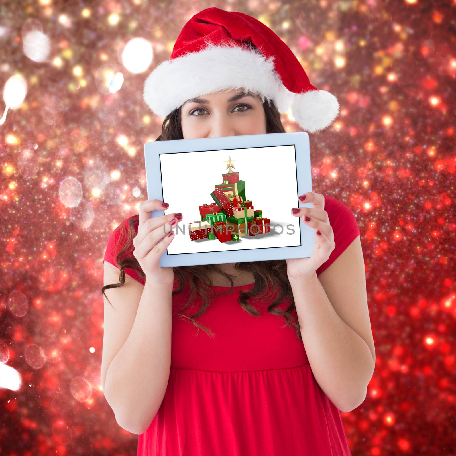 Festive brunette showing a tablet  against white snow and stars on red