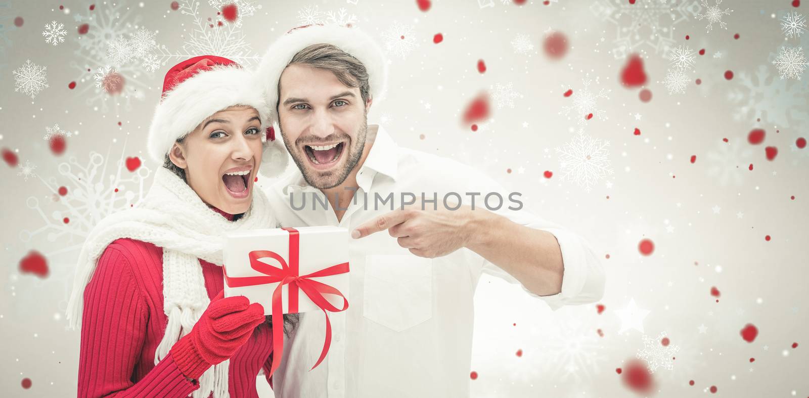 Festive young couple holding gift against snowflake pattern