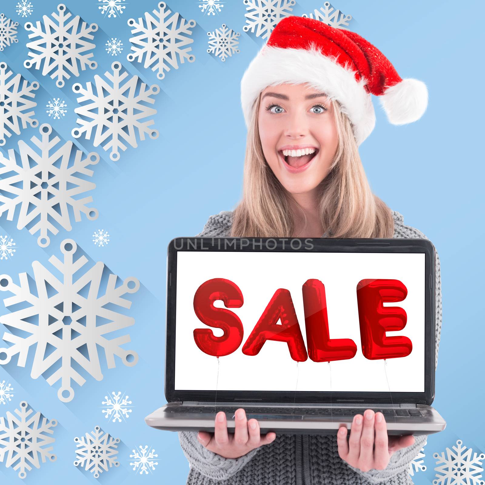 Festive blonde holding a laptop against snow flake frame design on blue